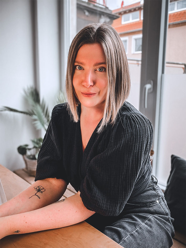 Anika Brust, zuständig für Büroleitung, Personal und Buchhaltung bei der Neu Bedachungen GmbH, sitzt an einem Tisch und blickt in die Kamera.